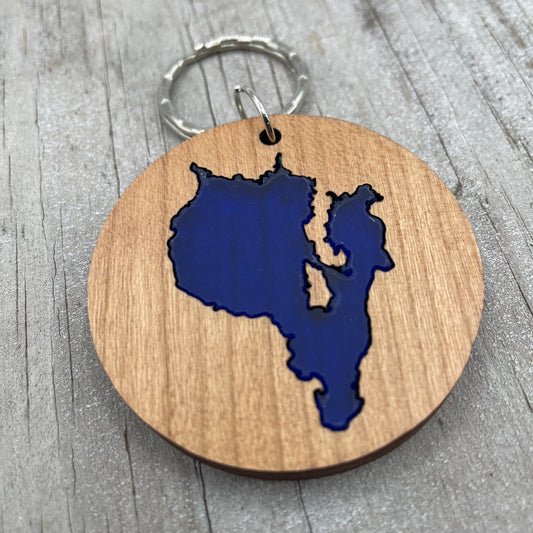Image shows the front side of a round keychain. Shows Sebago Lake, Maine in a cherry wood.